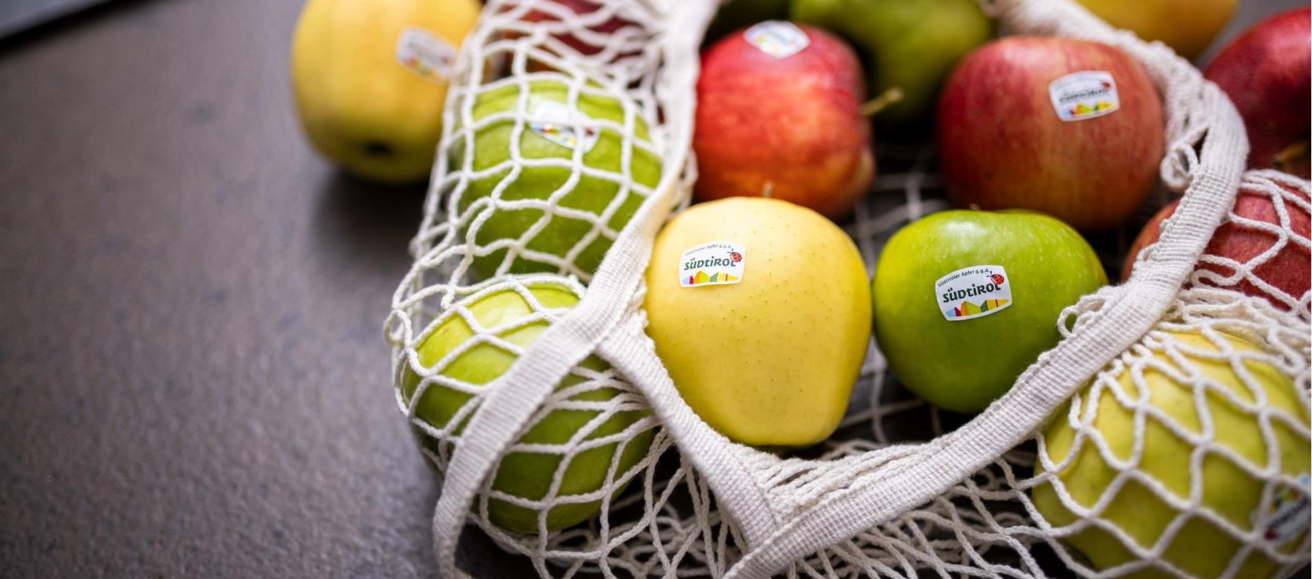 Una borsa di stoffa piena di mele altoatesine di diverse varietà.